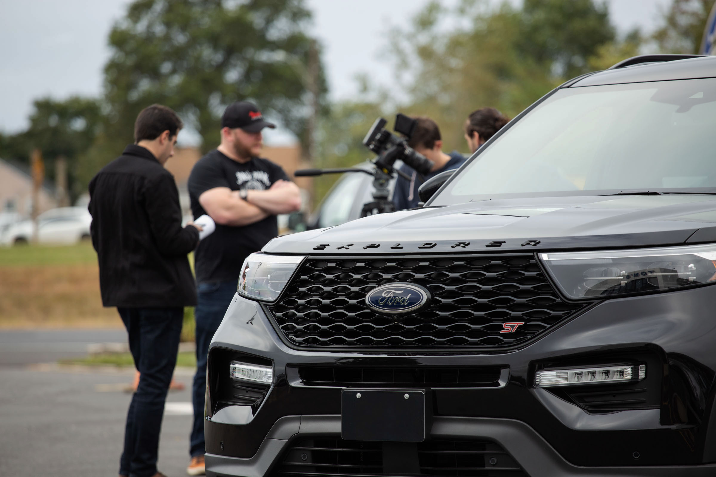 Ford Explorer with video production crew in background.