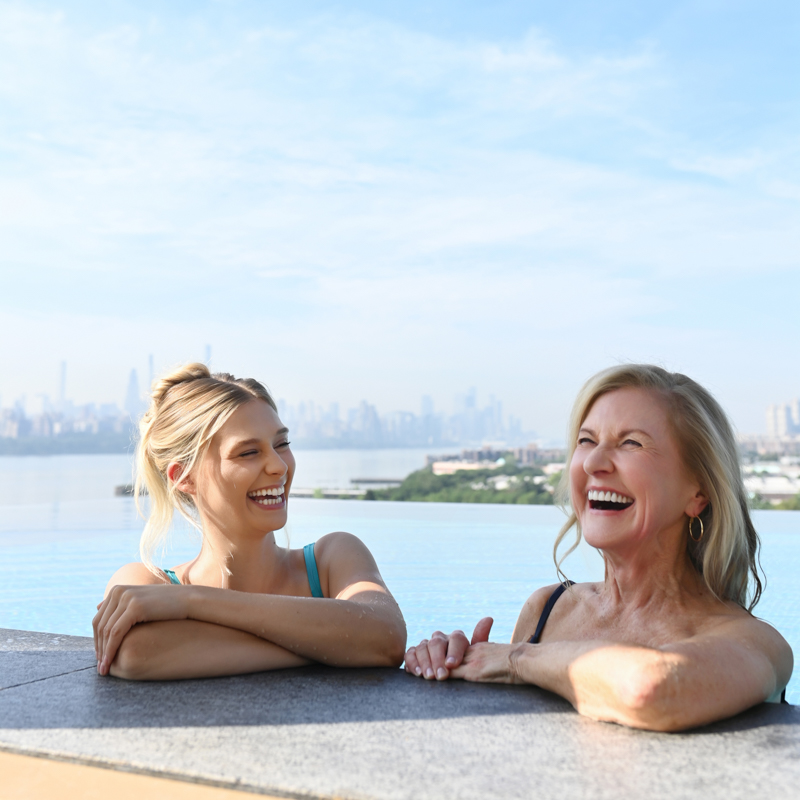 Lifestyle Photography of Two Women Laughing in SoJo Spa Club's Infinity Pool in Edgewater New Jersey