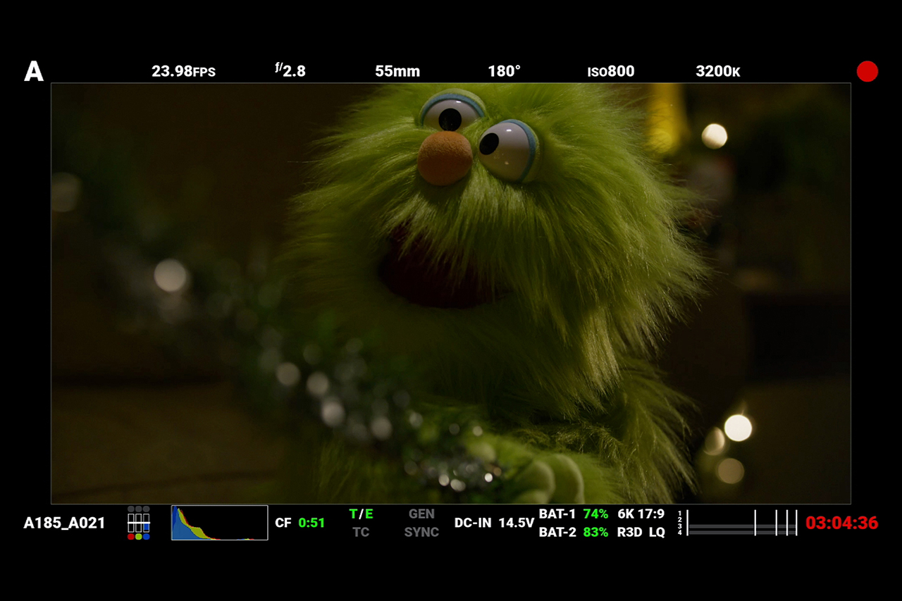 Red Digital Cinema camera monitor screenshot behind the scenes of Christmas short film, green monster puppet pulling garland.
